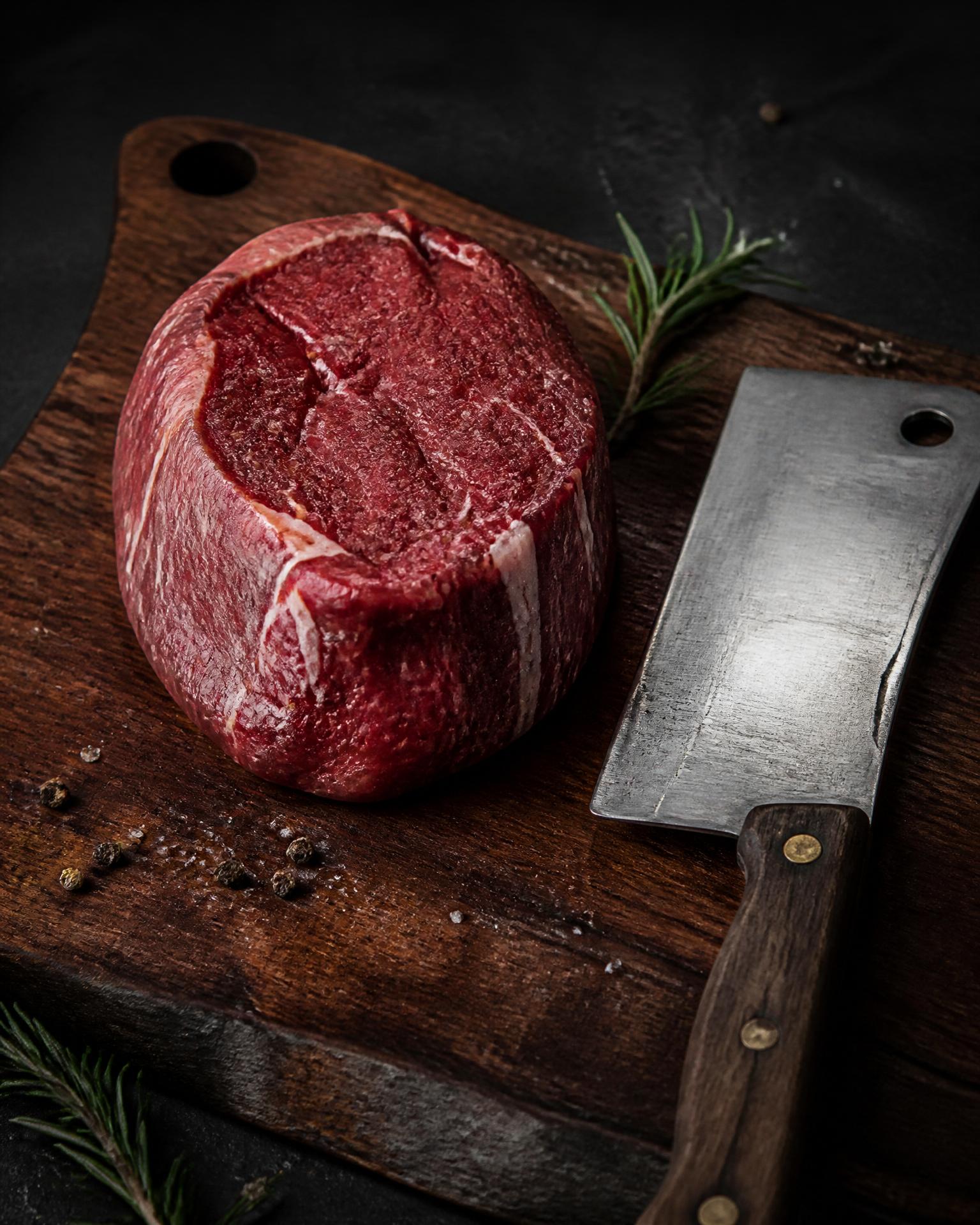 Premium dry-aged ribeye on slate with a shining butcher's knife